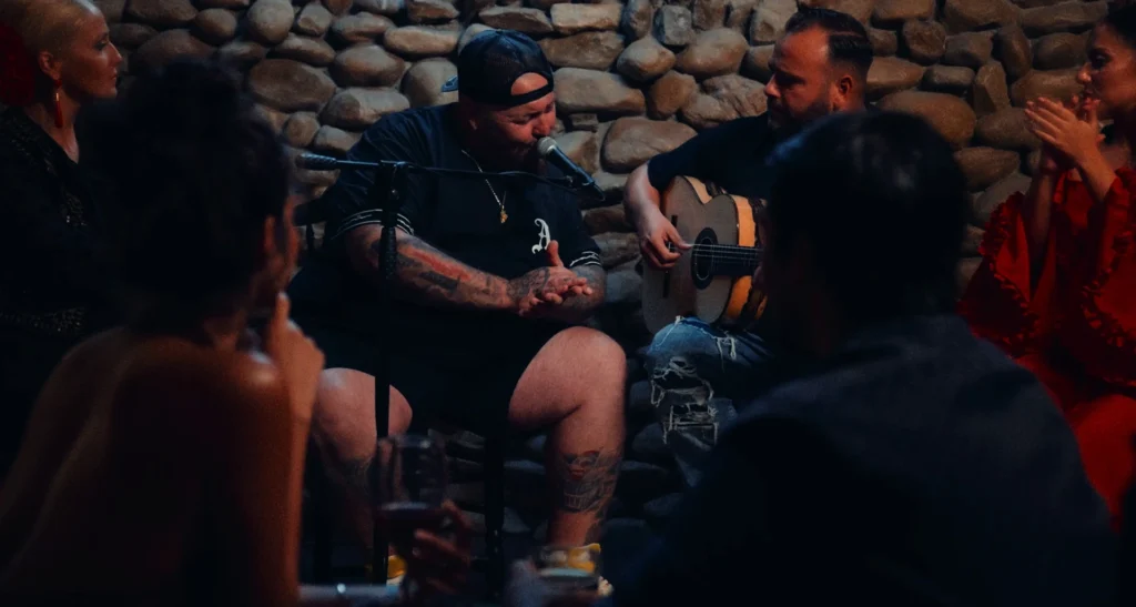 Gordo Master con guitarrista en un entorno flamenco en el videoclip Llámame loco